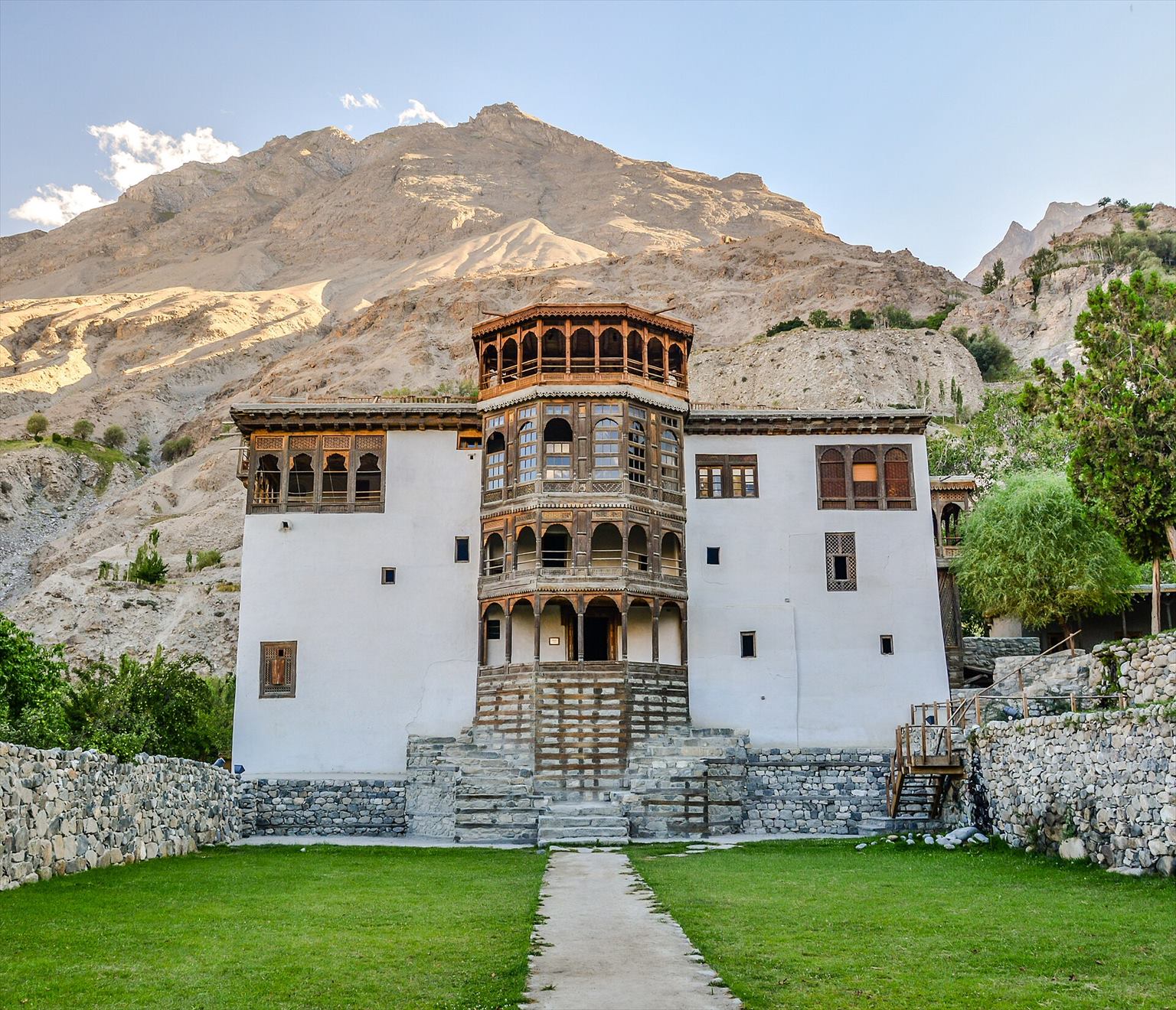 White and timber facade of Khaplu Palace against a rocky mountain slope