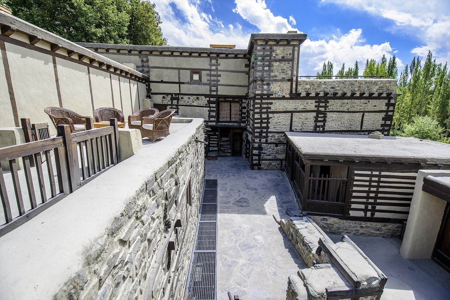 Stone, timber and plaster courtyard buildings at Shigar Fort under a blue sky